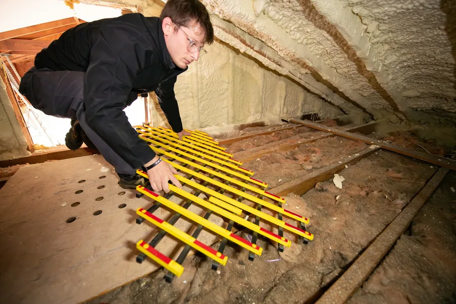 Installer working on the floor of a residential attic before insulation is blown in