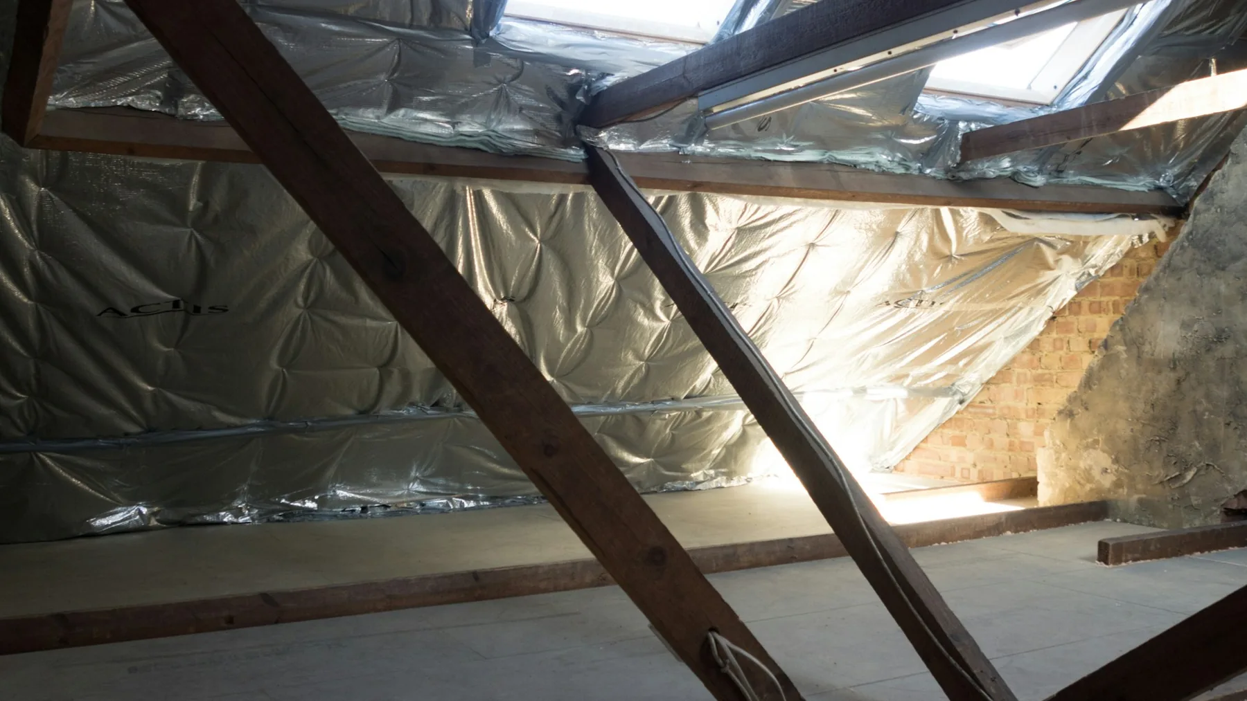 Attic interior with rafters and roof deck visible above the insulation line